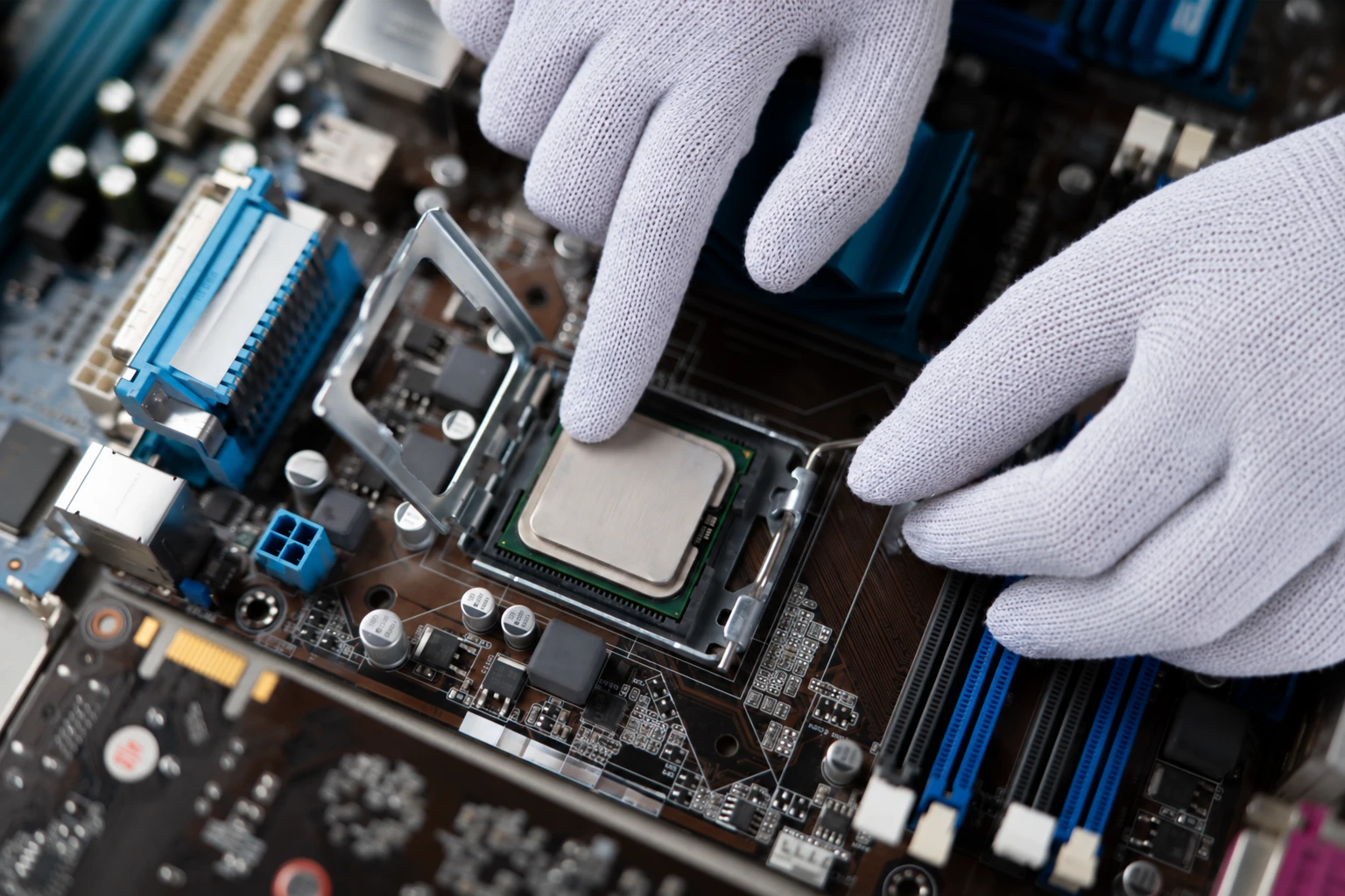 Techniker mit weißen ESD-Handschuhen setzt einen Prozessor in die Hauptplatine eines PCs ein